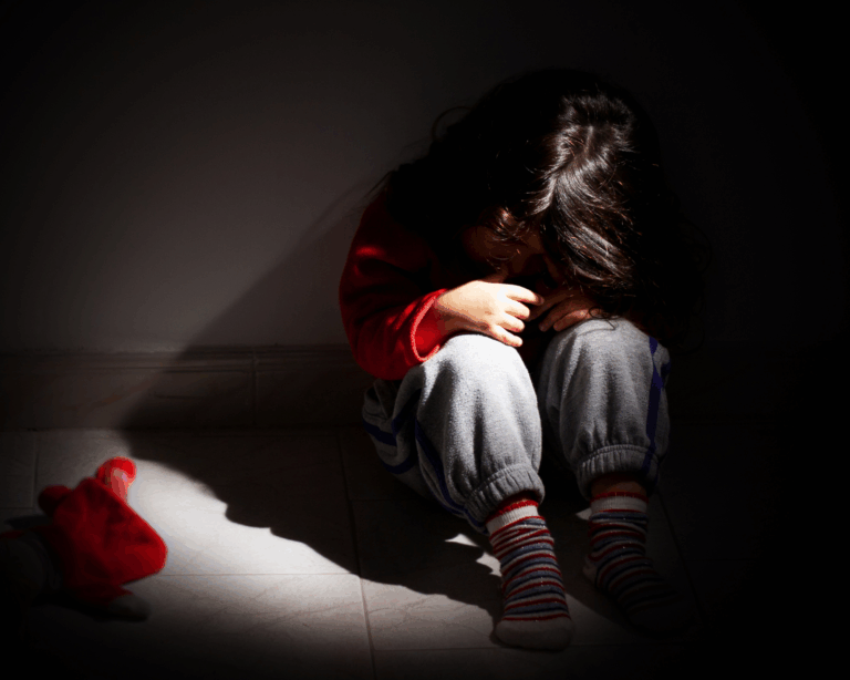 Young girl upset and sitting alone in the dark. Child abuse concept