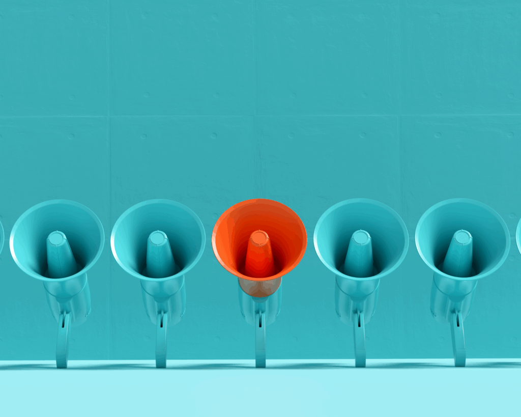 Blue megaphones in a row with one of them is in orange color on blue background. Concept of a differing message