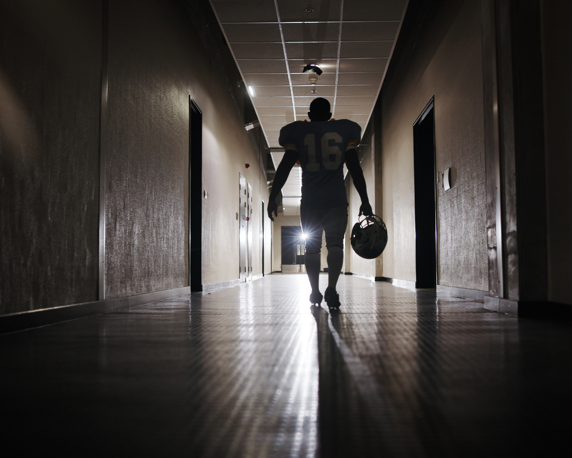 Back, football and light with man in corridor for sports competition, stadium match and game. Fitness, pro league player and athlete with person in tunnel for training, tournament and contest