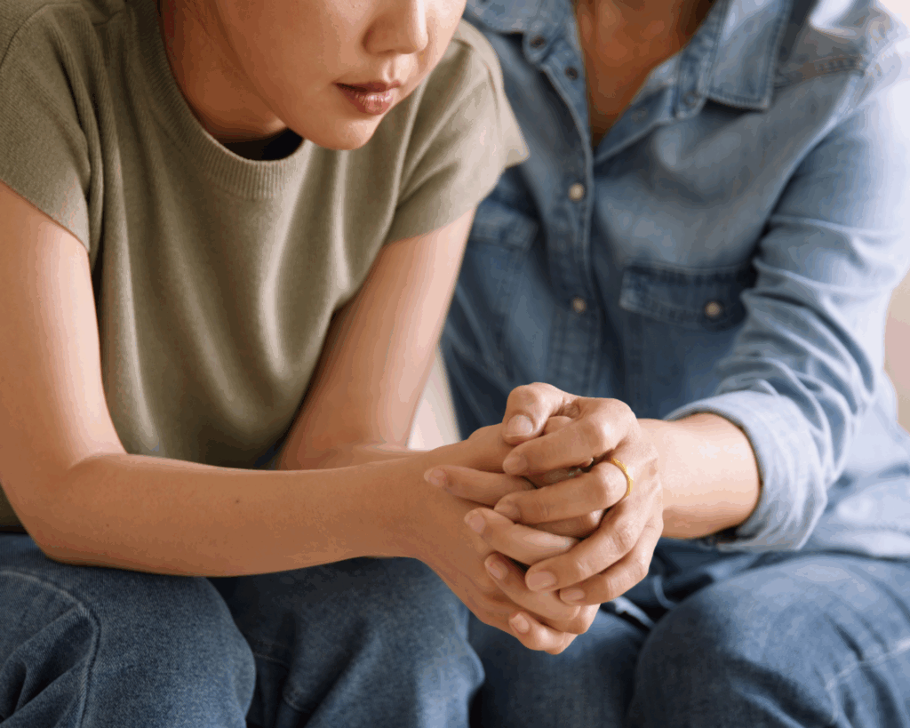 Portrait of a mom holding hands of her teen daughter to bring her trust and comfort. Mental health care and support concept