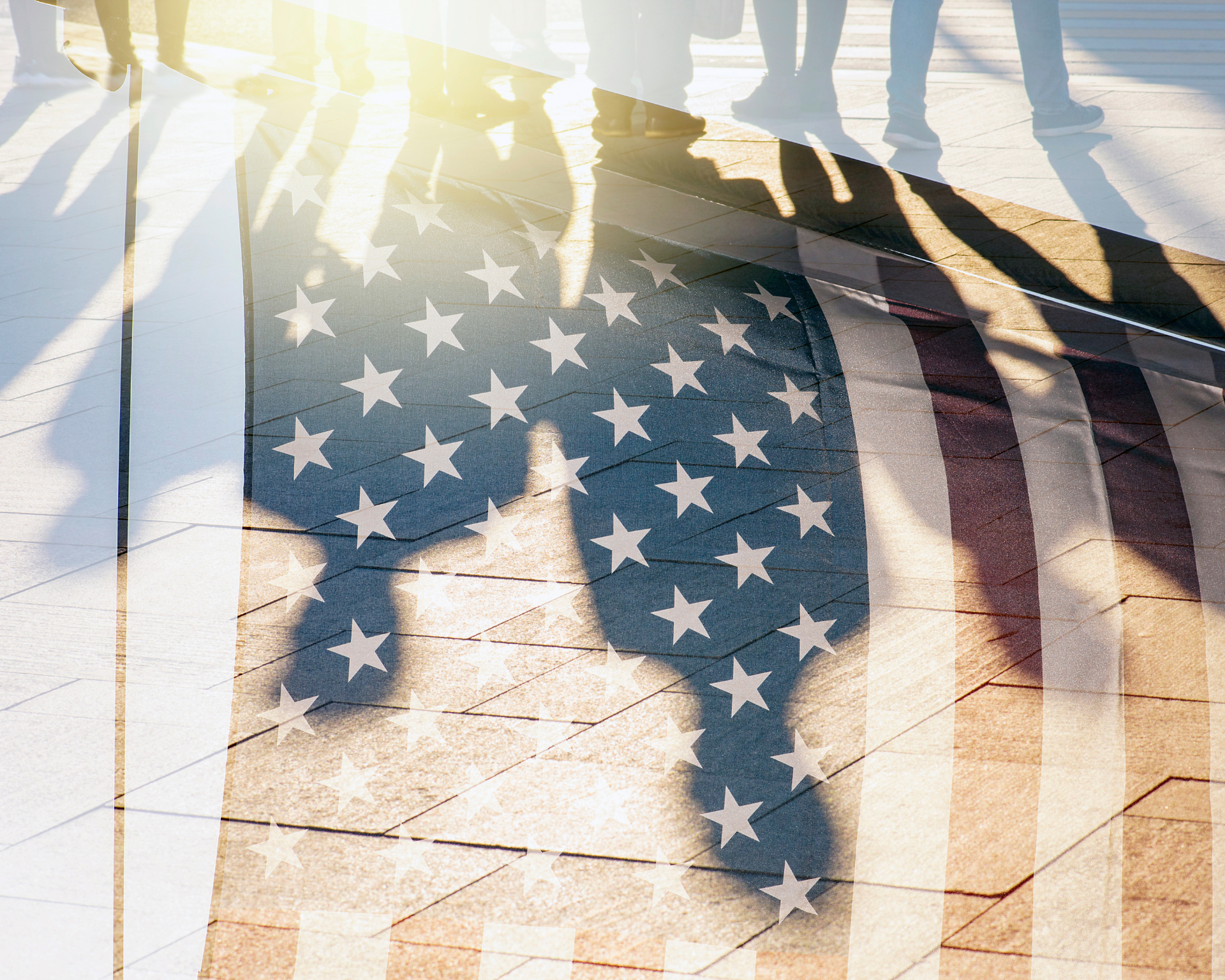 Shadows of people on a street overlayed across the American flag. Immigration concept