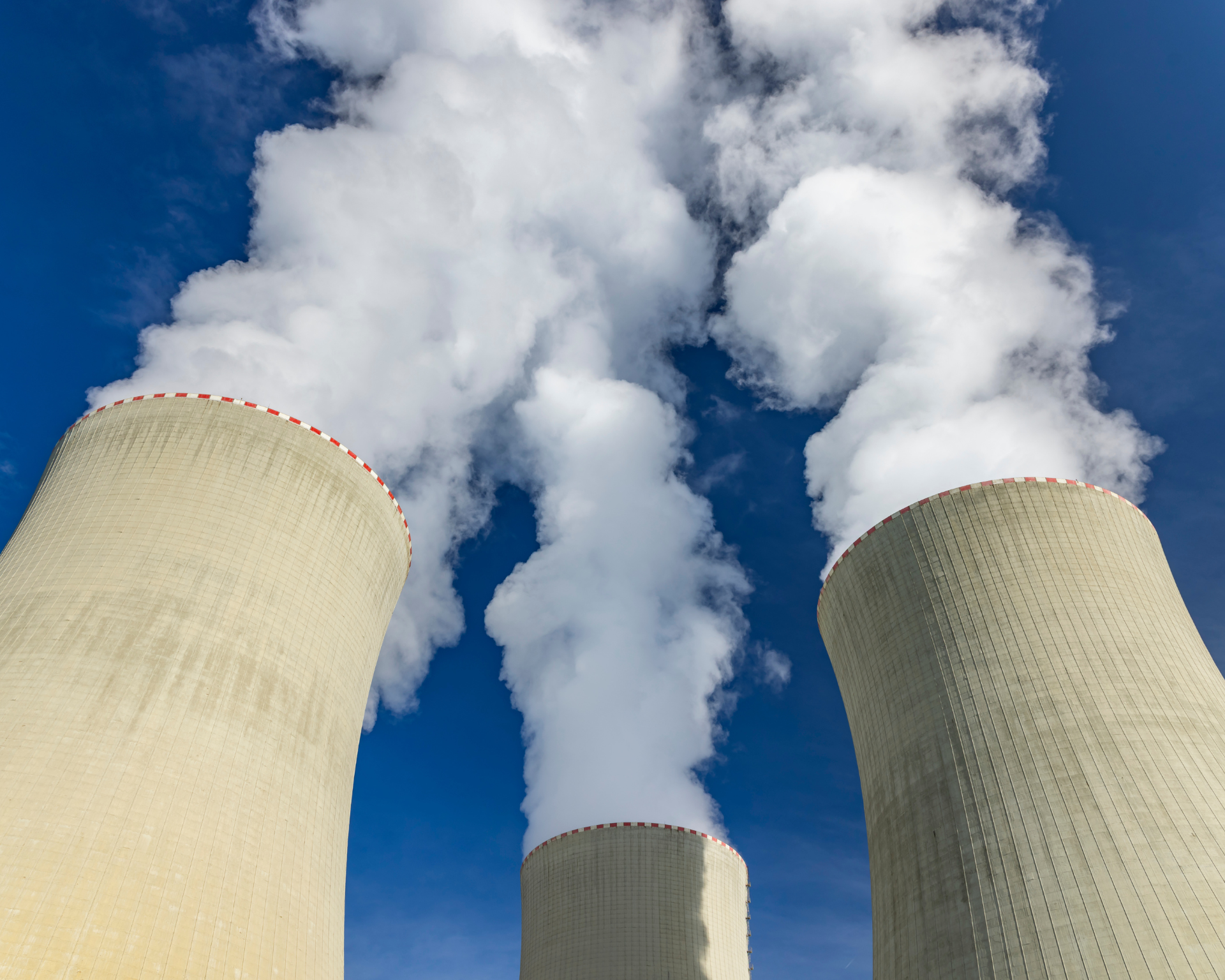Cooling towers releasing steam into a clear blue sky at a nuclear power complex