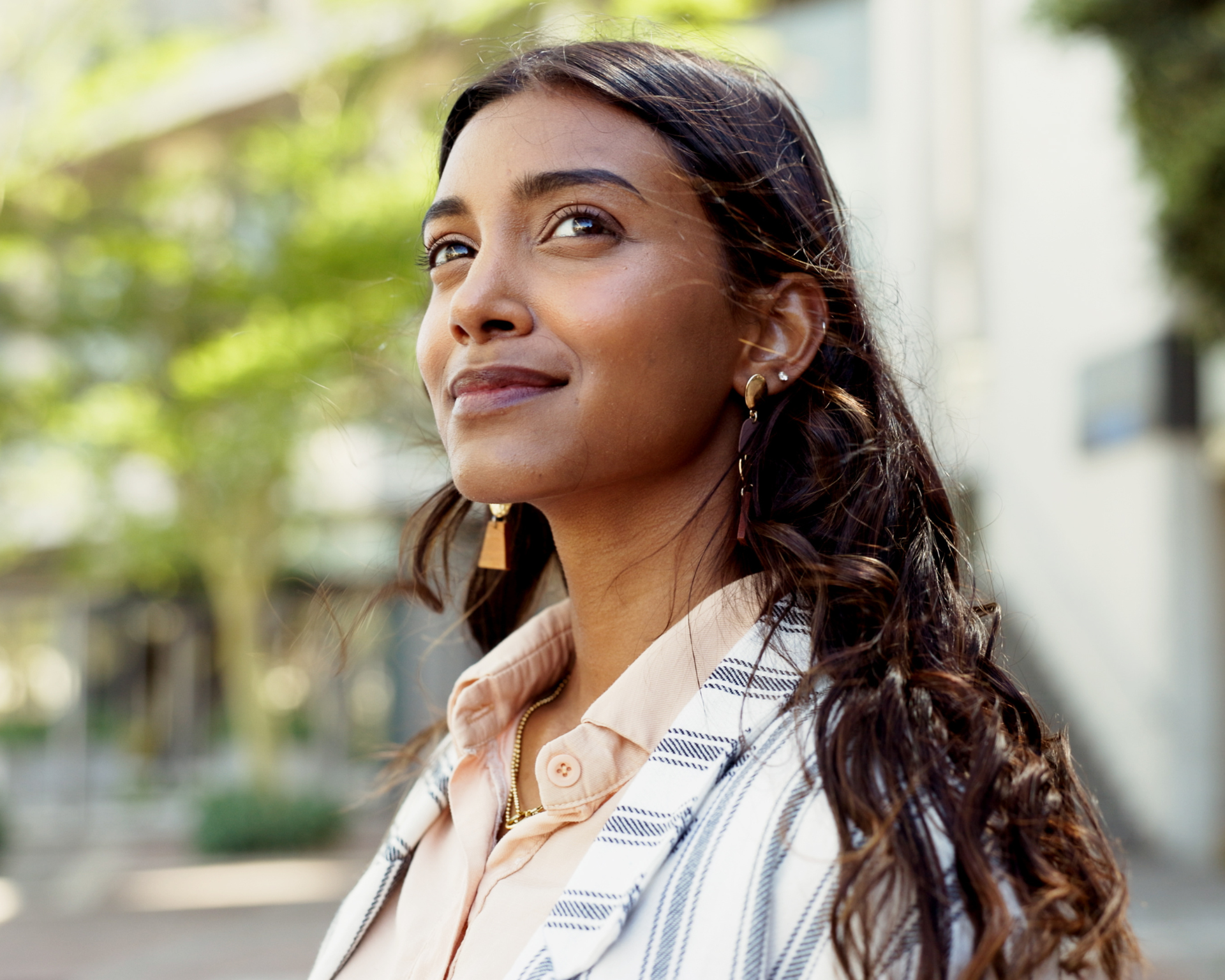 Portrait of a young woman on a city sidewalk looking off in distance. Meant to evoke motivation seeking