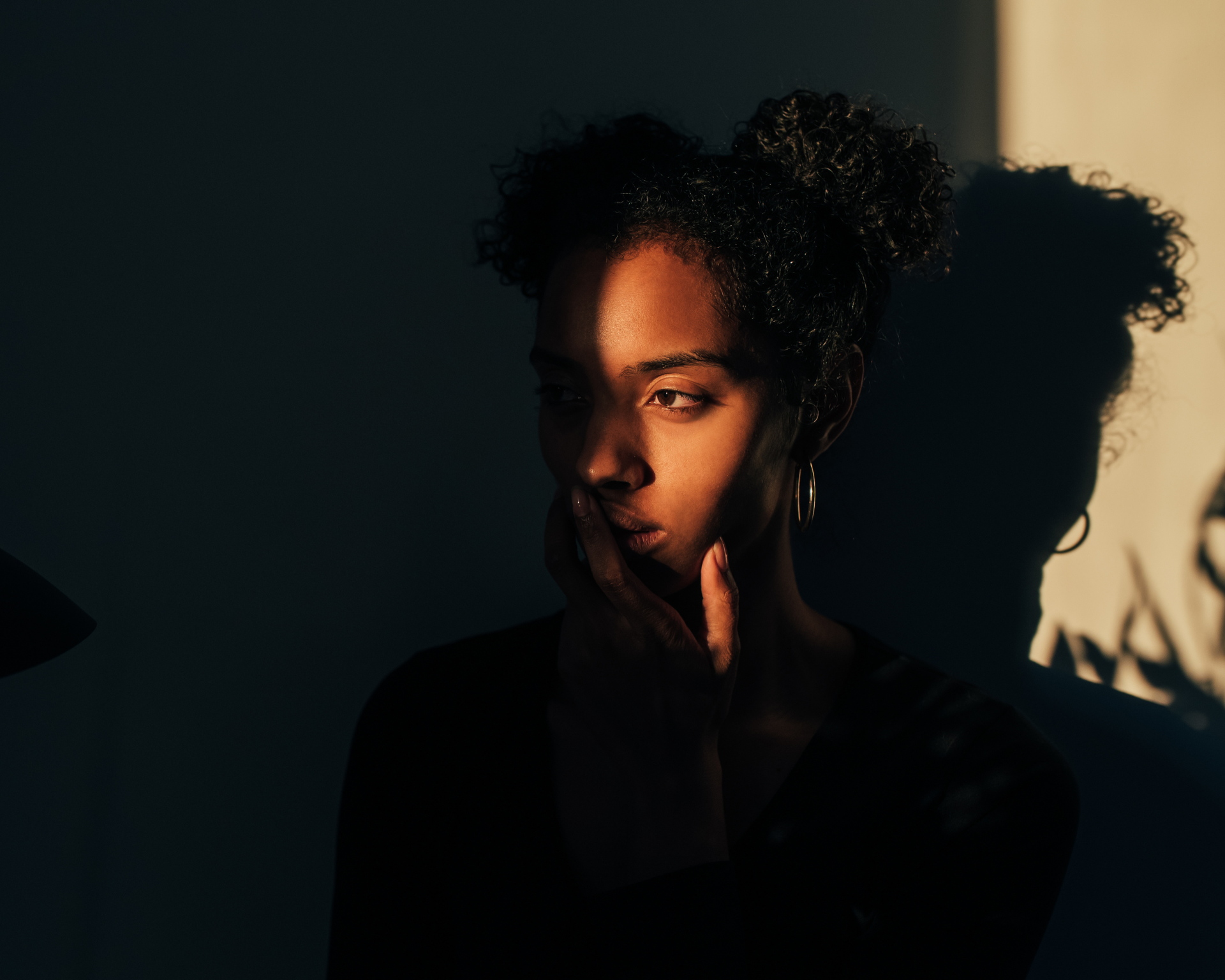 Woman standing near plant with shadow and light across her face. Neurodivergent concept