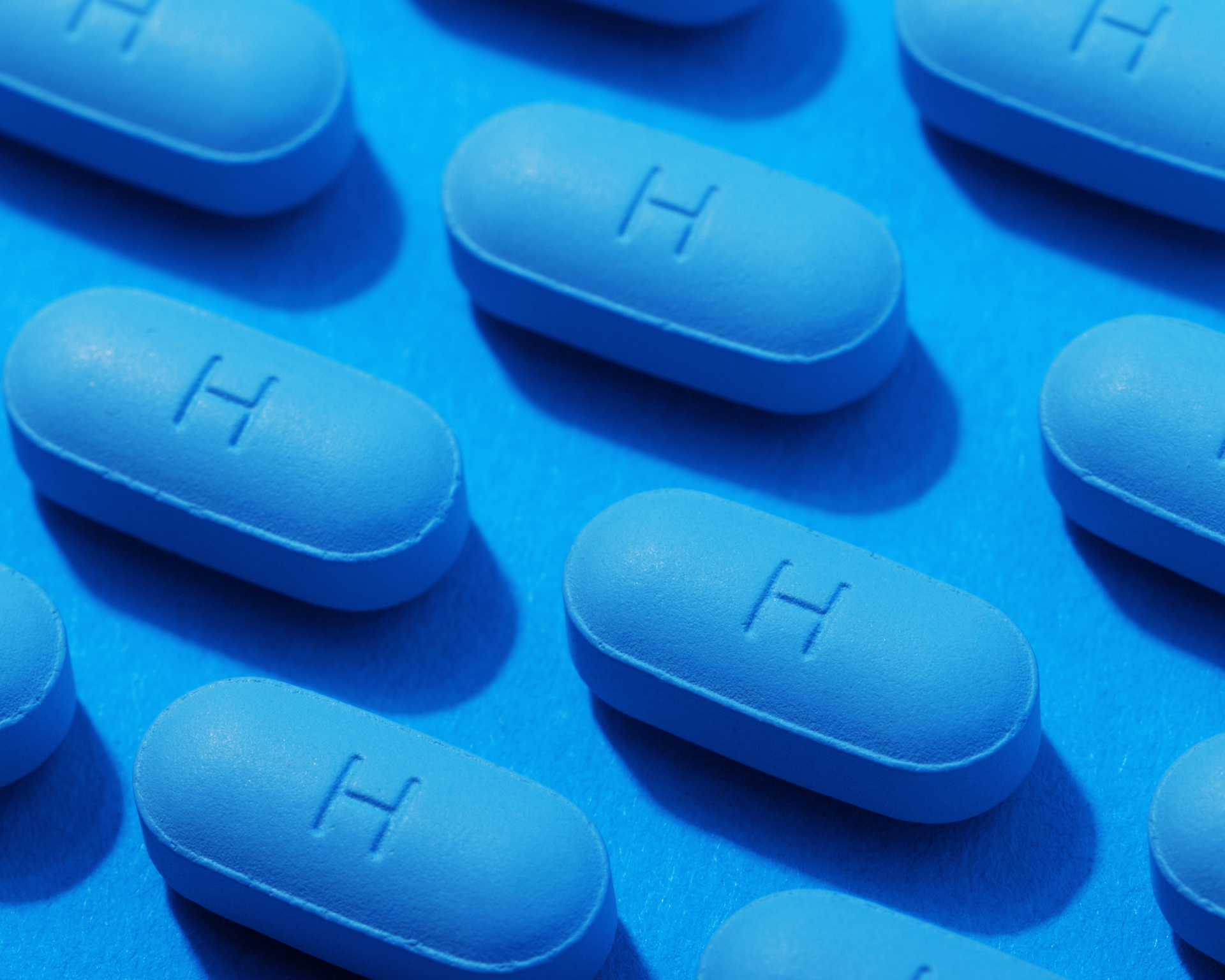 close up of blue PrEP pills lined up on blue background
