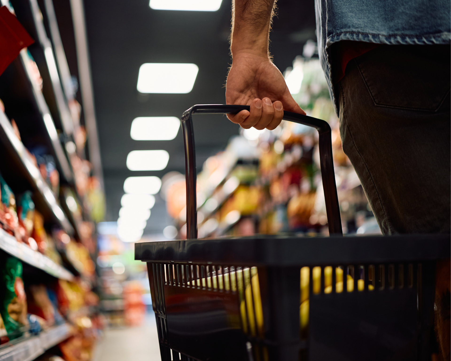 Close up of man with shopping basket buying groceries at the store. Food insecurity concept