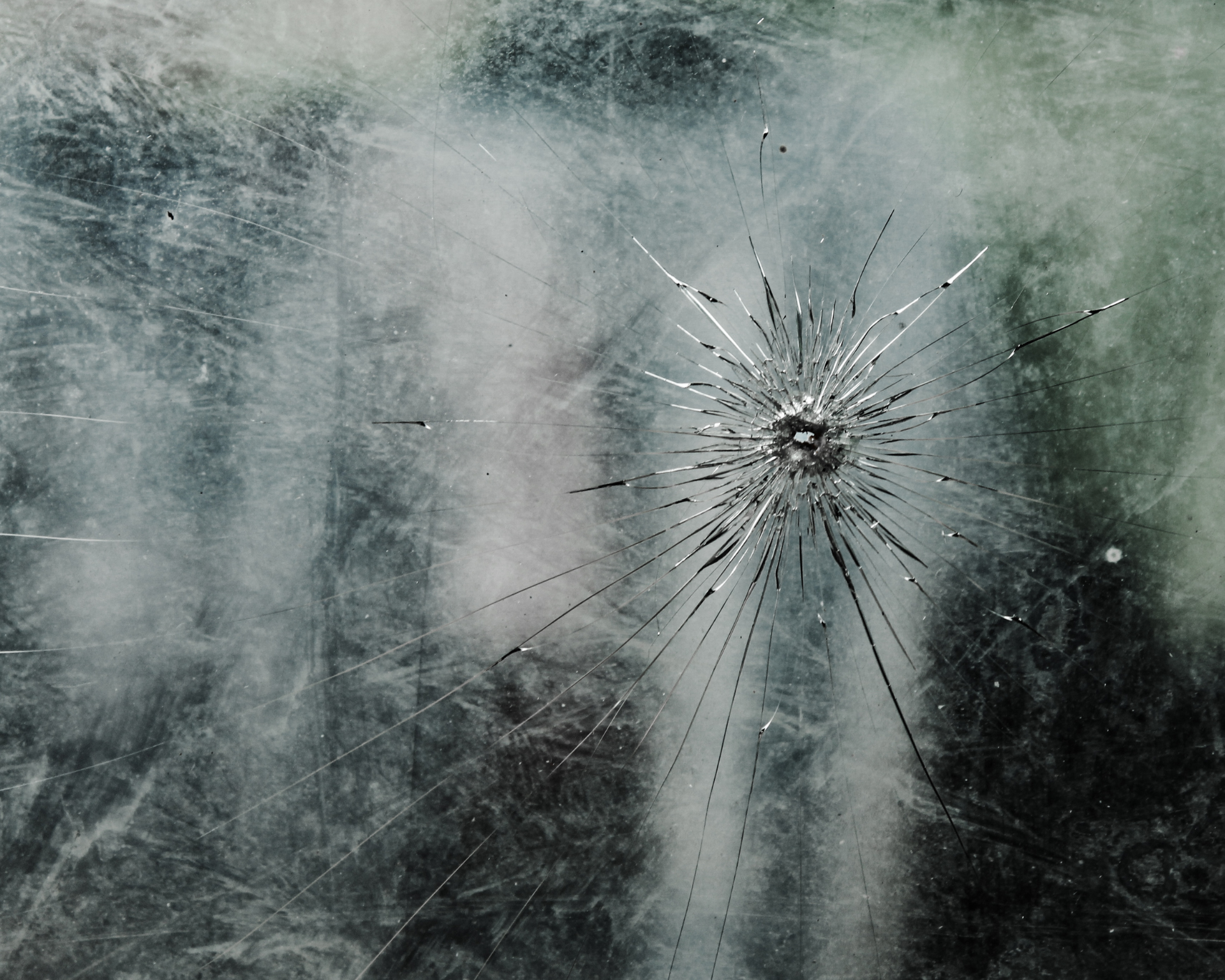 Close up of cracked glass texture with central impact point and radial cracks spreading dramatically. Gun violence and IPV concept