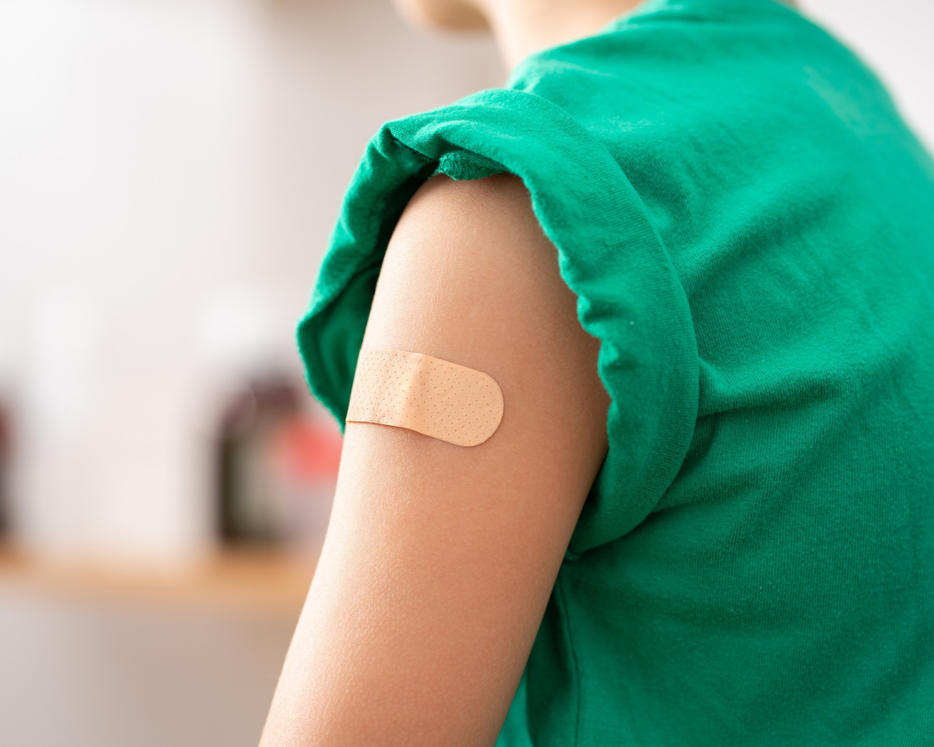 Young child with band-aid on upper arm, signifying recent vaccine inoculation