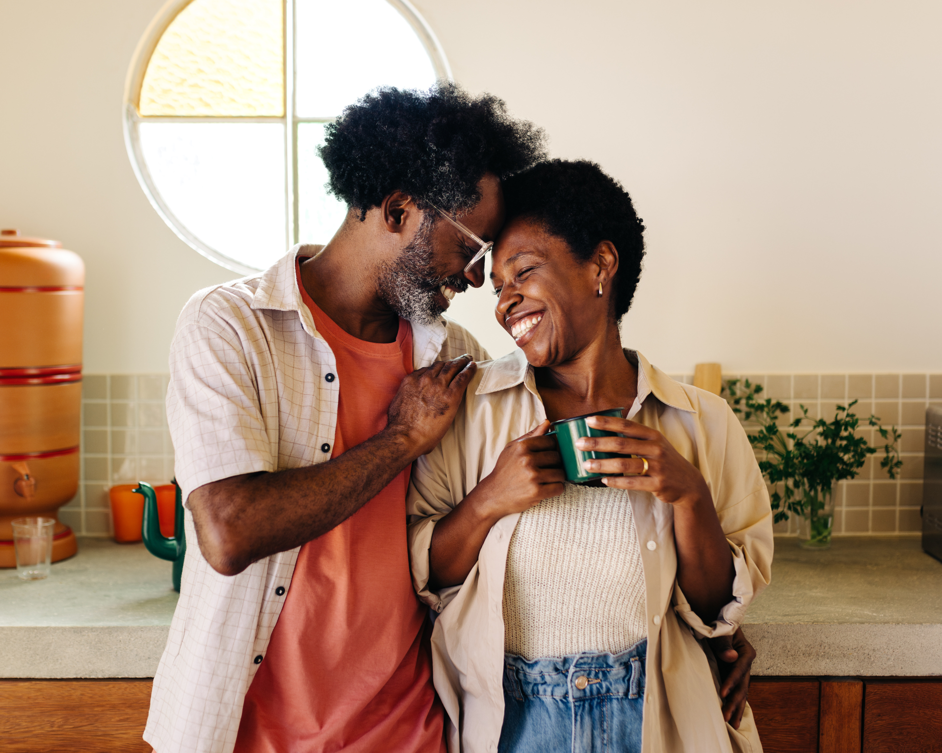 Portrait of an aging Black couple embracing in their kitchen
