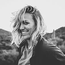 a woman smiling with a mountain in the background