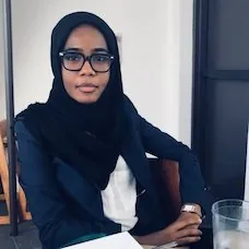 a woman wearing glasses and a scarf sitting at a table