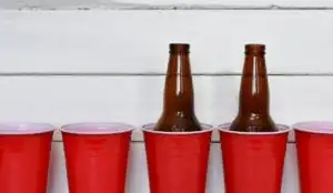 A row of red solo cups and two beer bottles