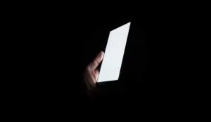 Hand holding a glowing smartphone in the dark