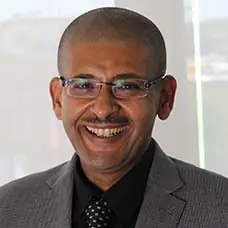 a man wearing glasses and a suit smiling
