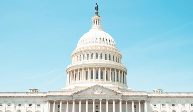 a white building with a statue on top with United States Capitol in the background