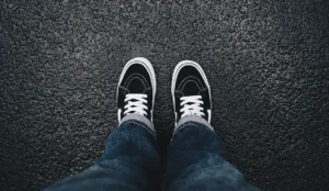 a person's legs and shoes on a wet road