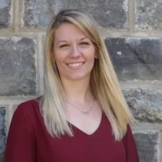 a woman smiling in front of a stone wall