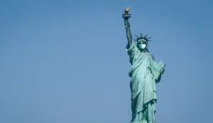 a statue of liberty wearing a face mask with Statue of Liberty in the background