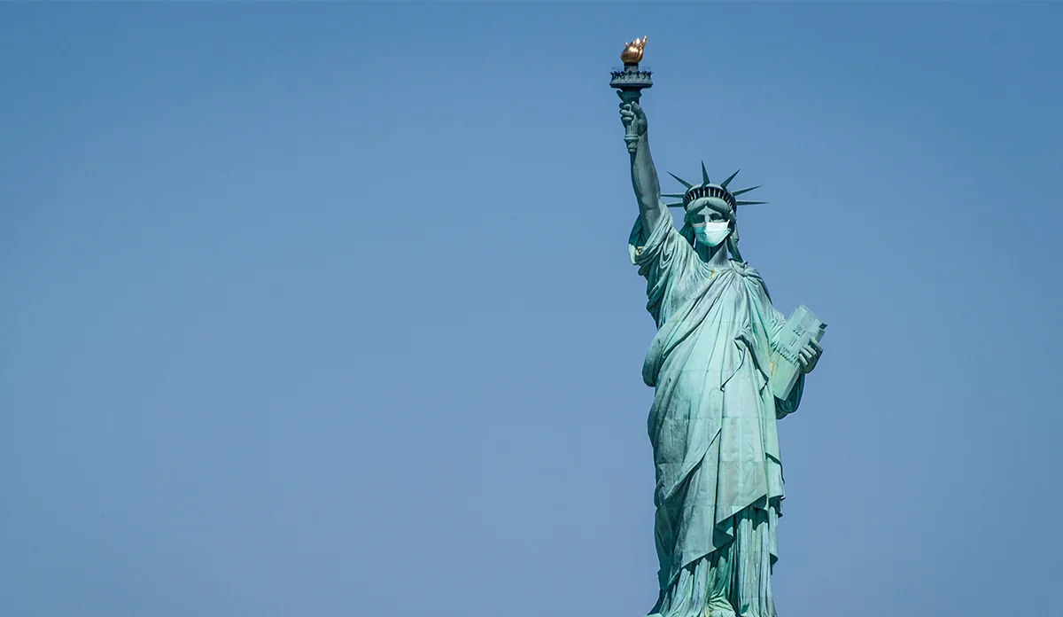 a statue of liberty wearing a face mask with Statue of Liberty in the background