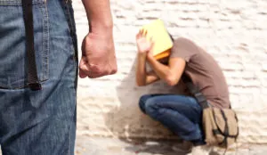 person with fist in foreground, person cowering in background