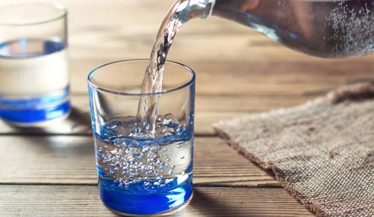 a glass with blue liquid and a bottle