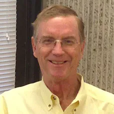 a man wearing glasses and a yellow shirt