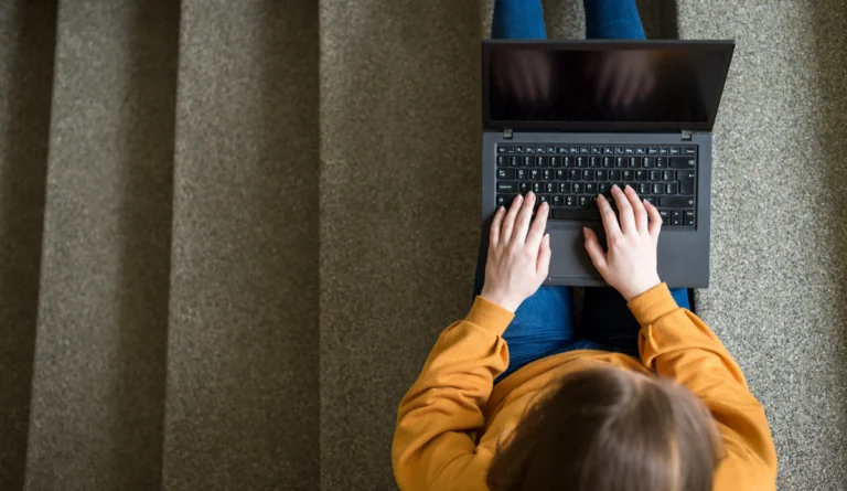 a person sitting on stairs using a laptop
