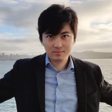 a man in a suit standing in front of water