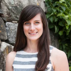 a woman smiling in front of a rock wall