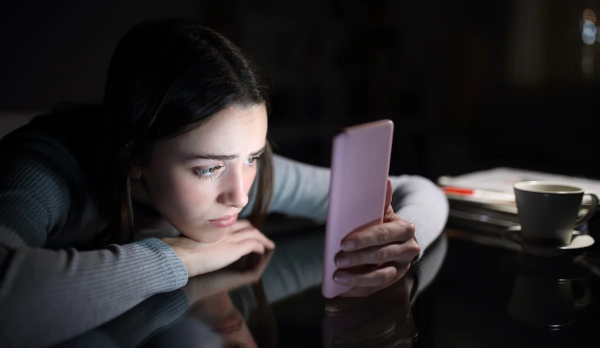 young, depressed girl scrolling through TikTok on her phone