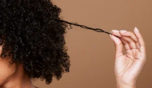 close up of Black woman pulling/twisting hair, implying the use of hair products