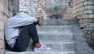 Young man sitting on stairs with head in hands, representing struggles with mental health