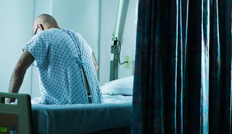 man sitting on side of hospital bed in emergency room