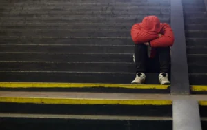 young man sitting on steps on street with head in hands