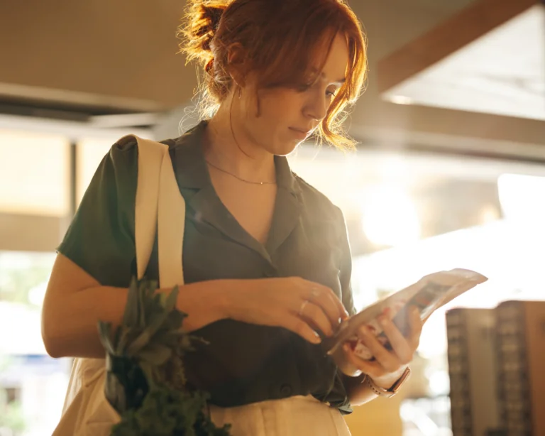 Young female shopper reading the label of a food product in a grocery store