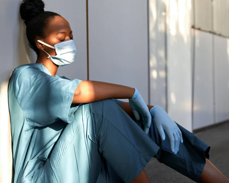 stressed health care worker sitting on the hospital floor