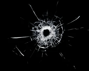 a bullet hole with cracks in the glass isolated on a black background