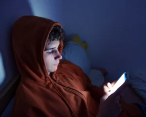 Teen boy scrolling on phone late at night