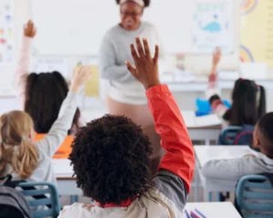 young children eagerly raising hands in a classroom setting. education concept