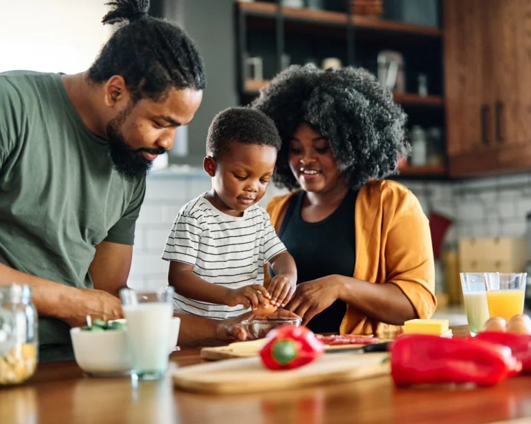 Portrait of mother, father and son preparing and eating breakfast in the kitchen at home.
