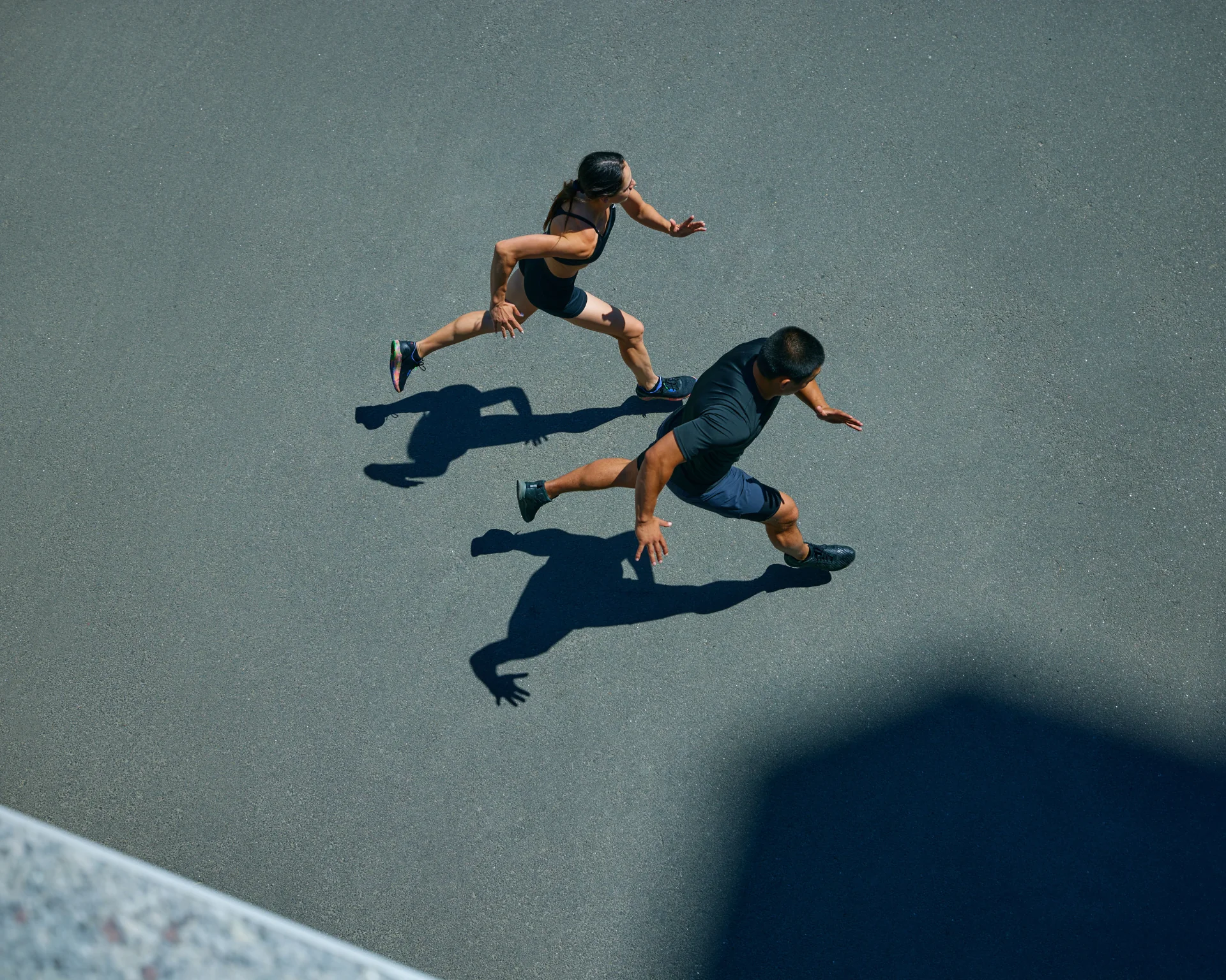 Young, athlete man and woman in sporty attire running together during pair workout on sunny summer day. Movement concept