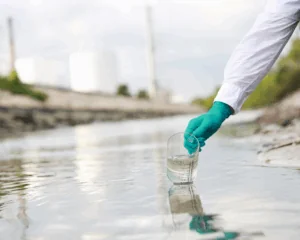 gloved hand of scientist taking a sample of wastewater