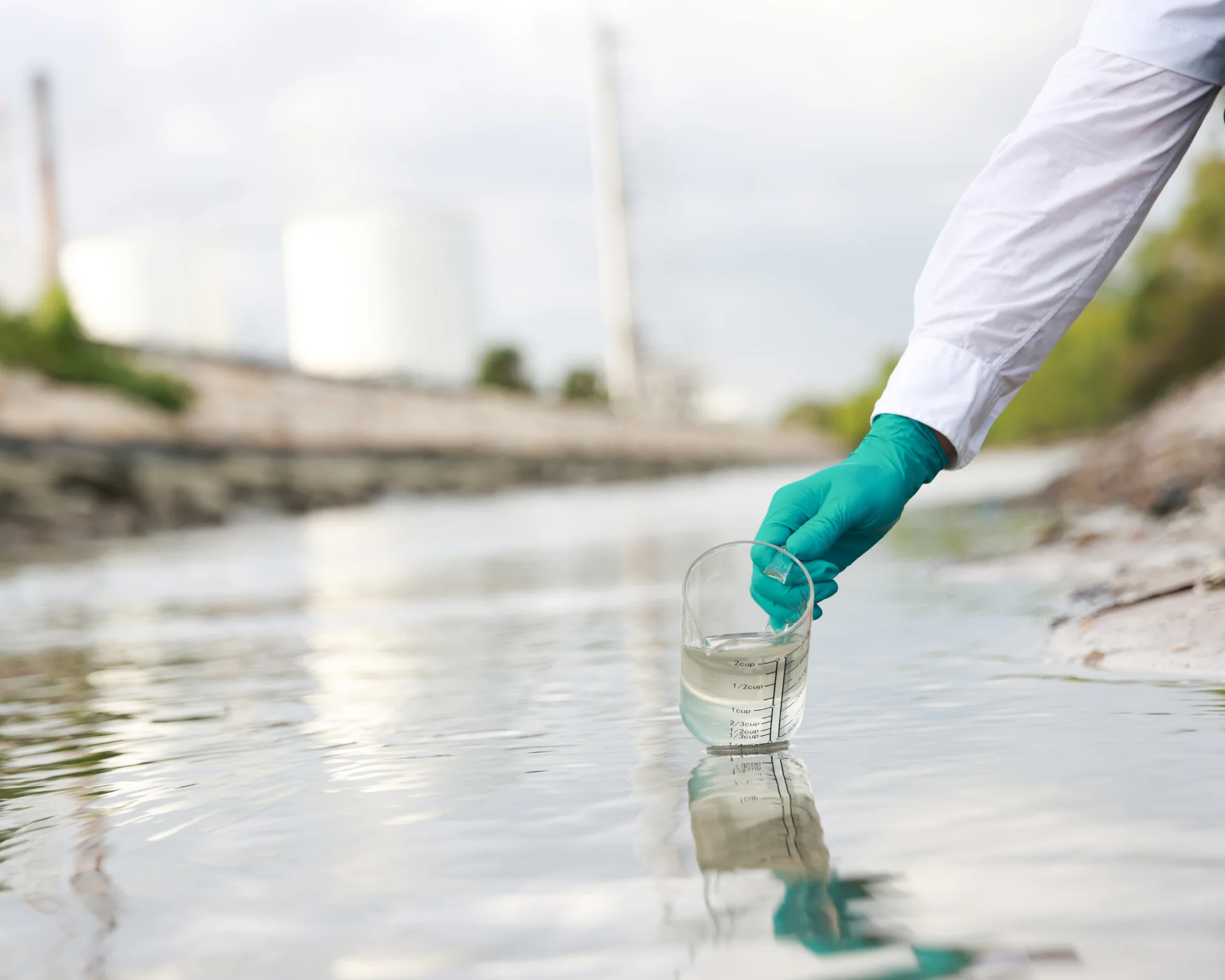 gloved hand of scientist taking a sample of wastewater