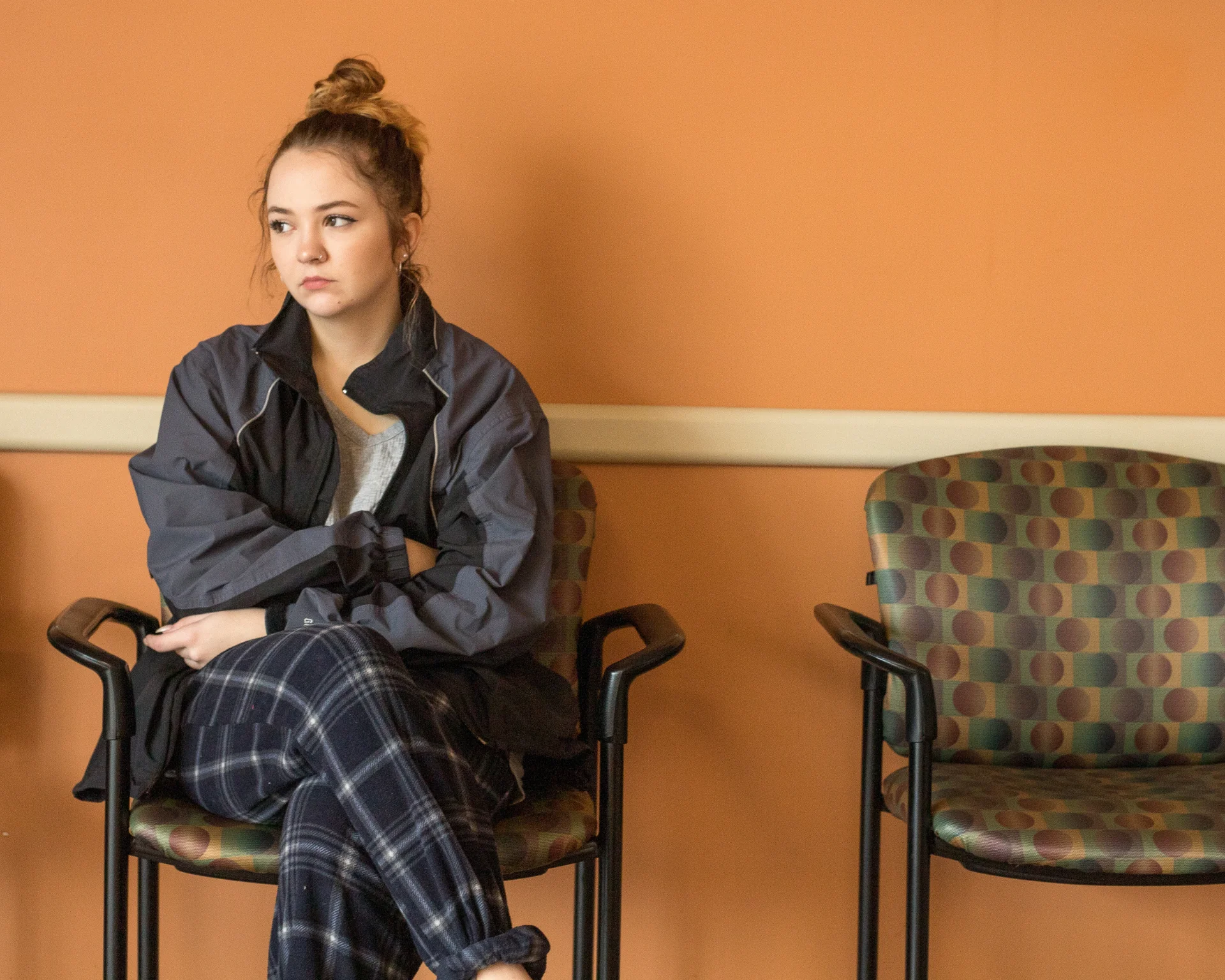 Young woman sitting alone in a waiting room. Crisis pregnancy center concept