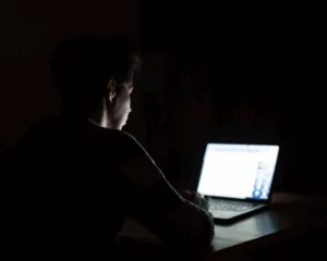young man on computer in dark room. manosphere concept