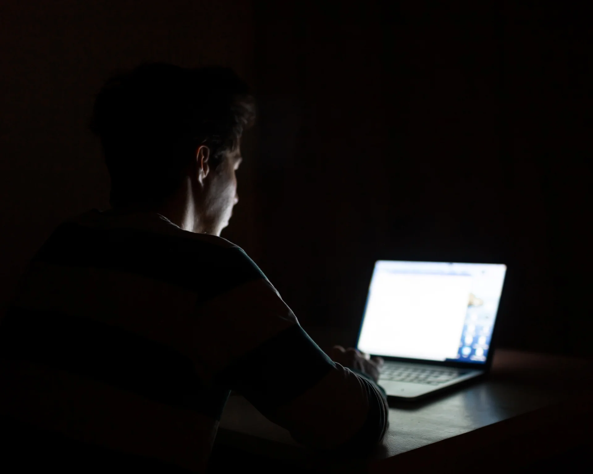 young man on computer in dark room. manosphere concept