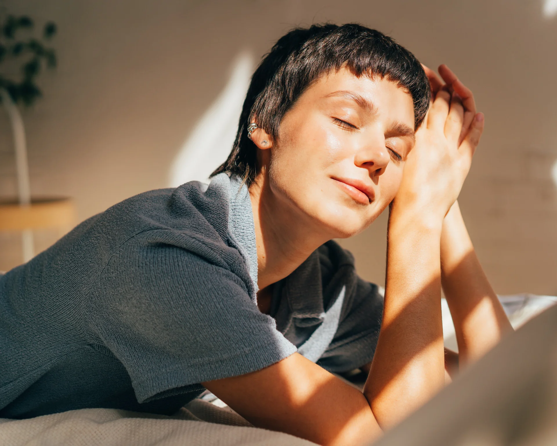 A woman lies on a bed in bright sunlight from the window. Restful sleep concept