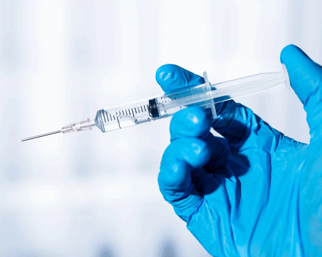 Syringe in gloved hand on white background. Vaccination concept