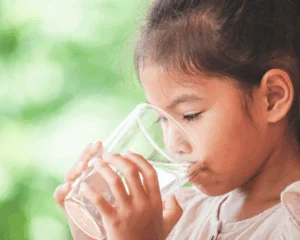 Close-up of young girl drinking water from a glass outdoors