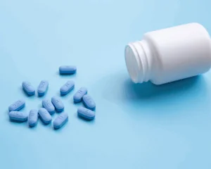 spilled bottle of PrEP pills on blue background